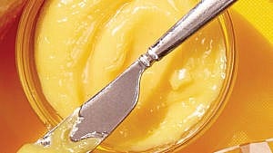 Bright yellow mayonnaise with a butter knife on top of the jar