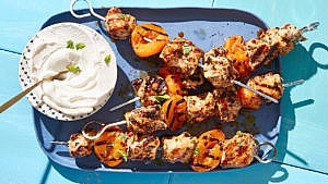 Apricot-Glazed Chicken Skewers with Sumac and Mint on a blue plate with a side of labneh