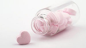 A heart-shaped pill in a clear bottle, representing sex supplements for women