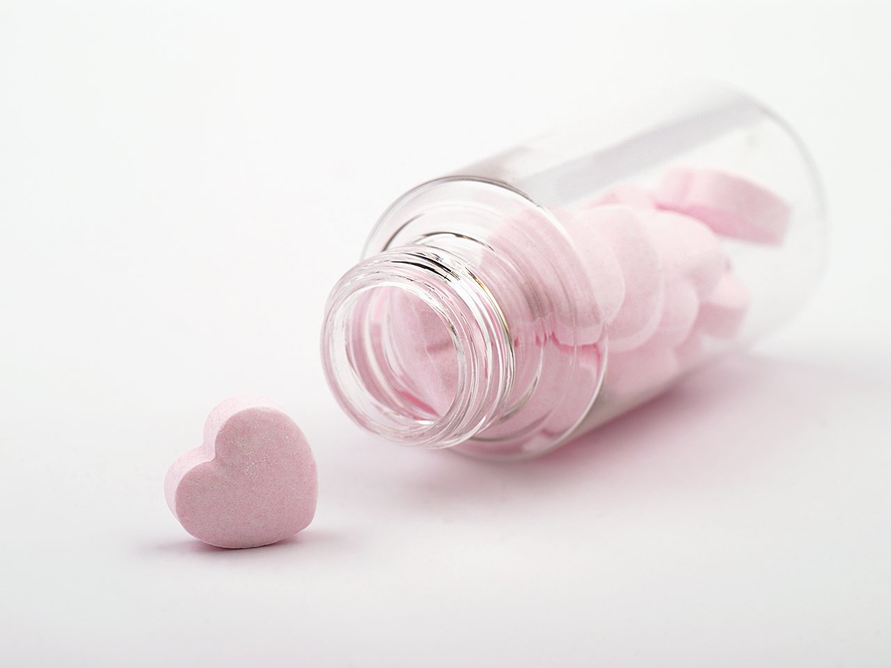 A heart-shaped pill in a clear bottle, representing sex supplements for women