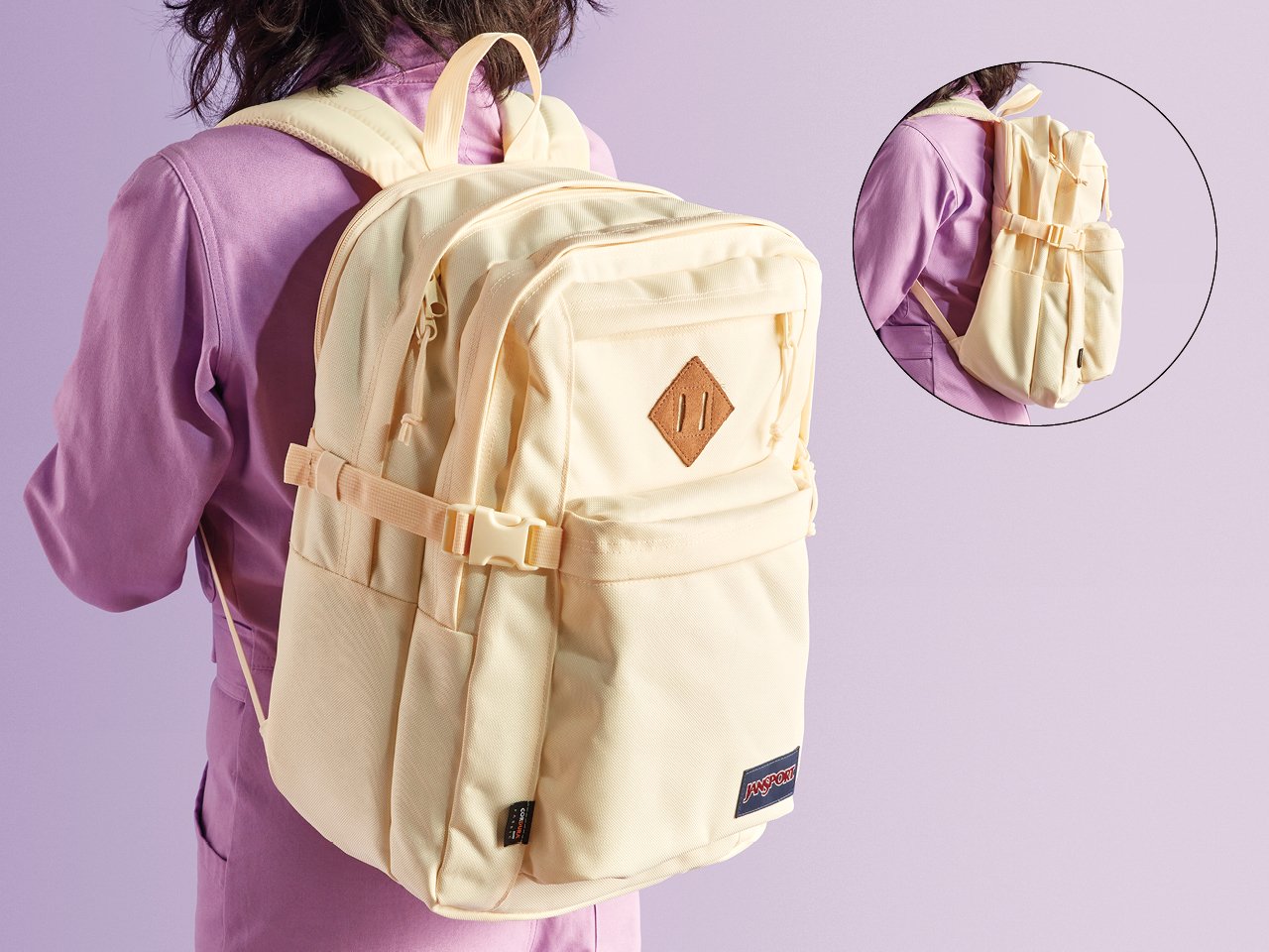 A photo of the back of a woman in a lilac jumpsuit wearing a cream backpack
