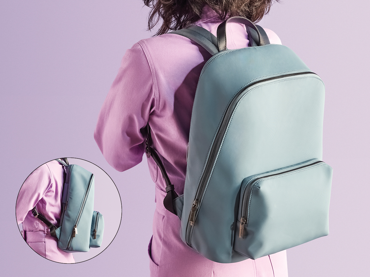 A photo of the back of a woman in a lilac jumpsuit wearing a light blue backpack