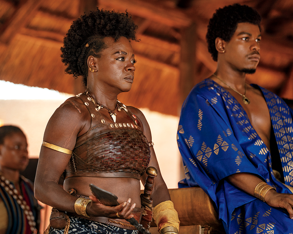 A film still of movie The Woman King showing actress Viola Davis and her male co-star in war attire looking in the distance