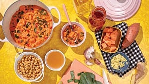 A bird's eye view of a table with a dish of peanut stew and various ingredients