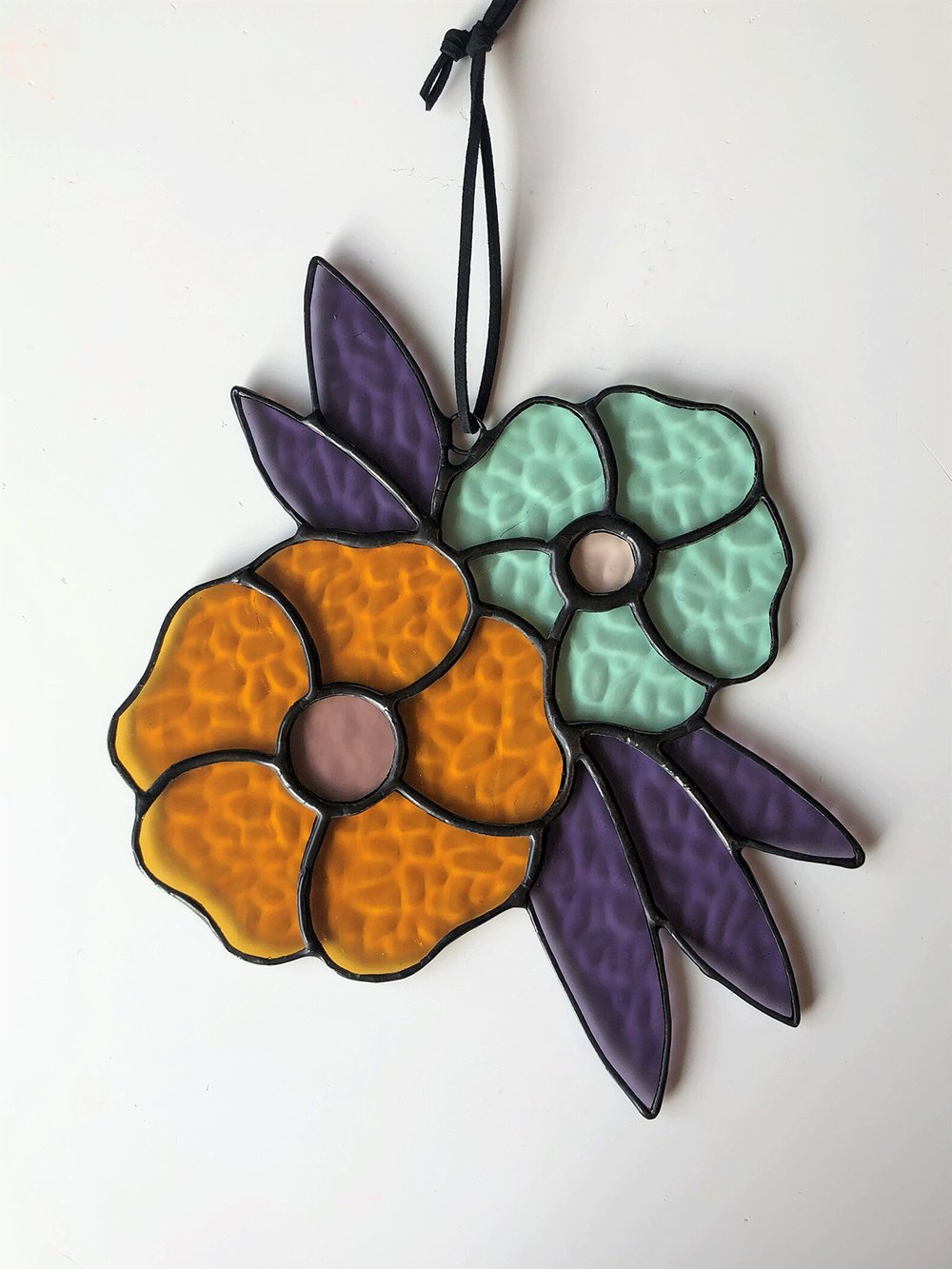Teal and orange flowers made from stained glass by Canadian maker Copper and Came.