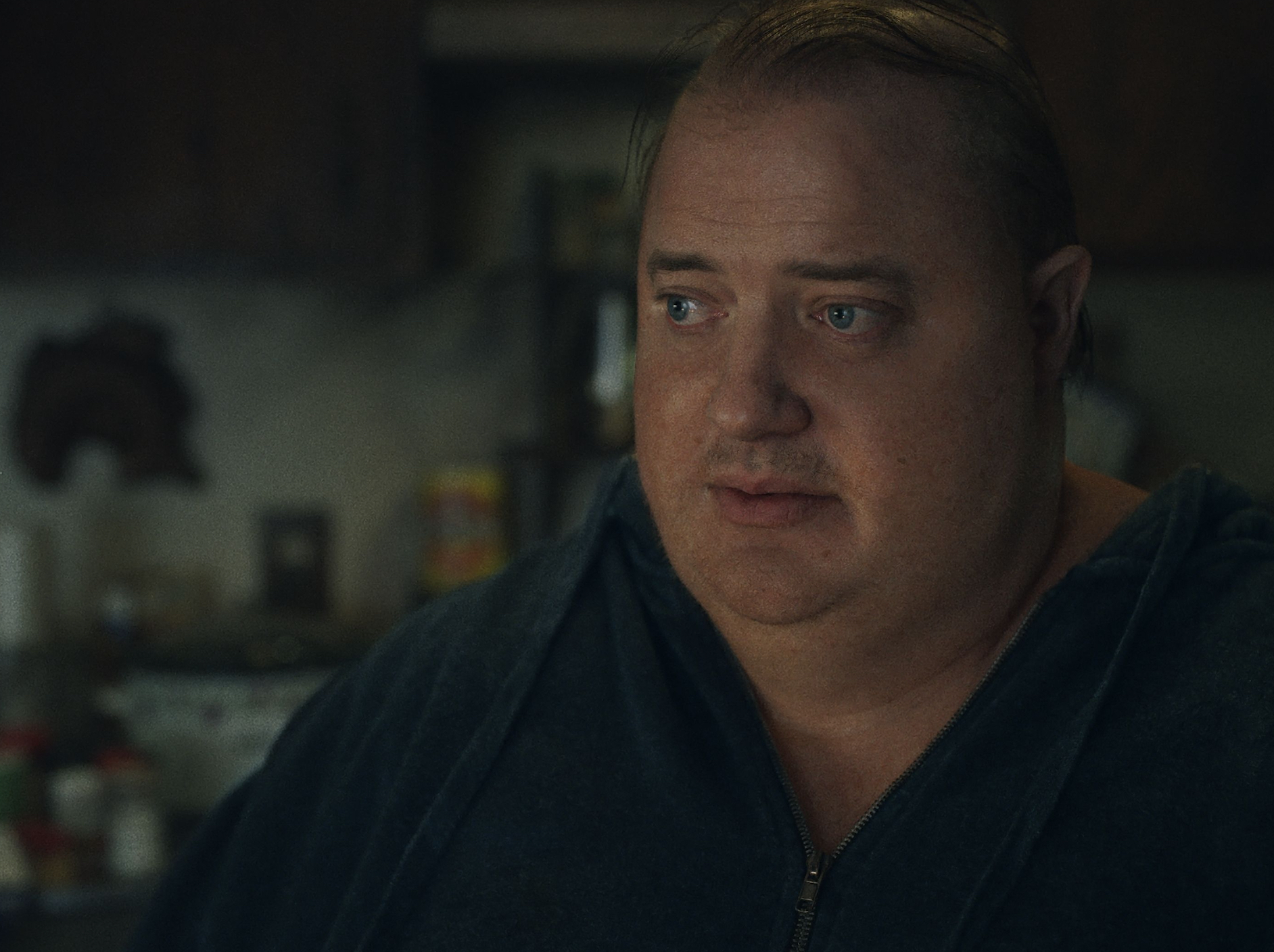 Actor Brendan Fraser in character as The Whale, a 600-pound man, looks off camera with a pained expression on his face.
