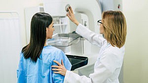 A doctor prepares a woman for a mammogram