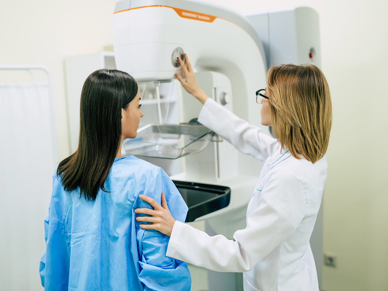 A doctor prepares a woman for a mammogram