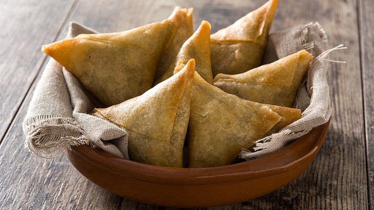 Samsa or samosas with meat and vegetables on wooden table.