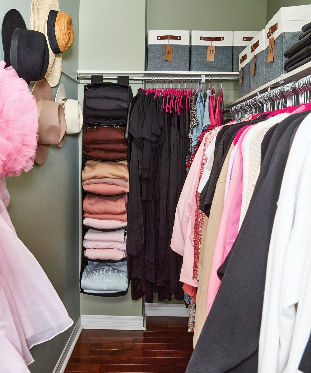 Sarah Nicole Landry's organized walk-in closet, with hats hung along the wall on the left, a hanging clothes organizer on the far wall and clothes hanging on pink velvet clothes hangers.