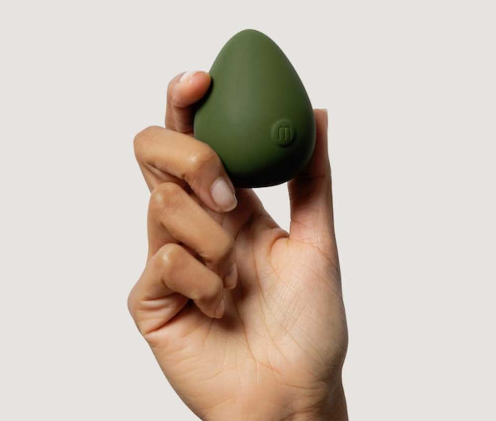 A hand holding an egg-shaped forest green vibrator from Maude.