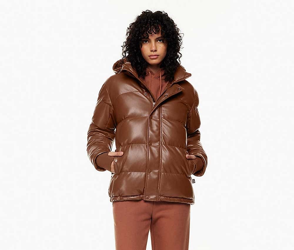 A woman wearing a brown cropped faux leather Super Puff coat from Aritzia.