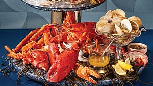 a seafood tower made of glass cake stands laden with oysters, clams and lobster