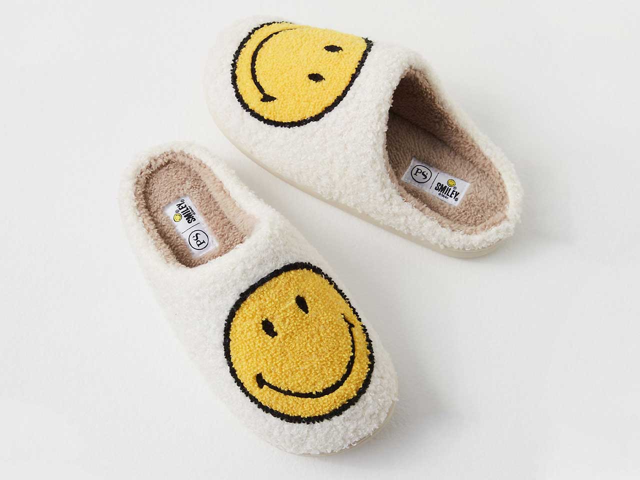 A pair of white slippers with yellow Smiley faces from Free People.