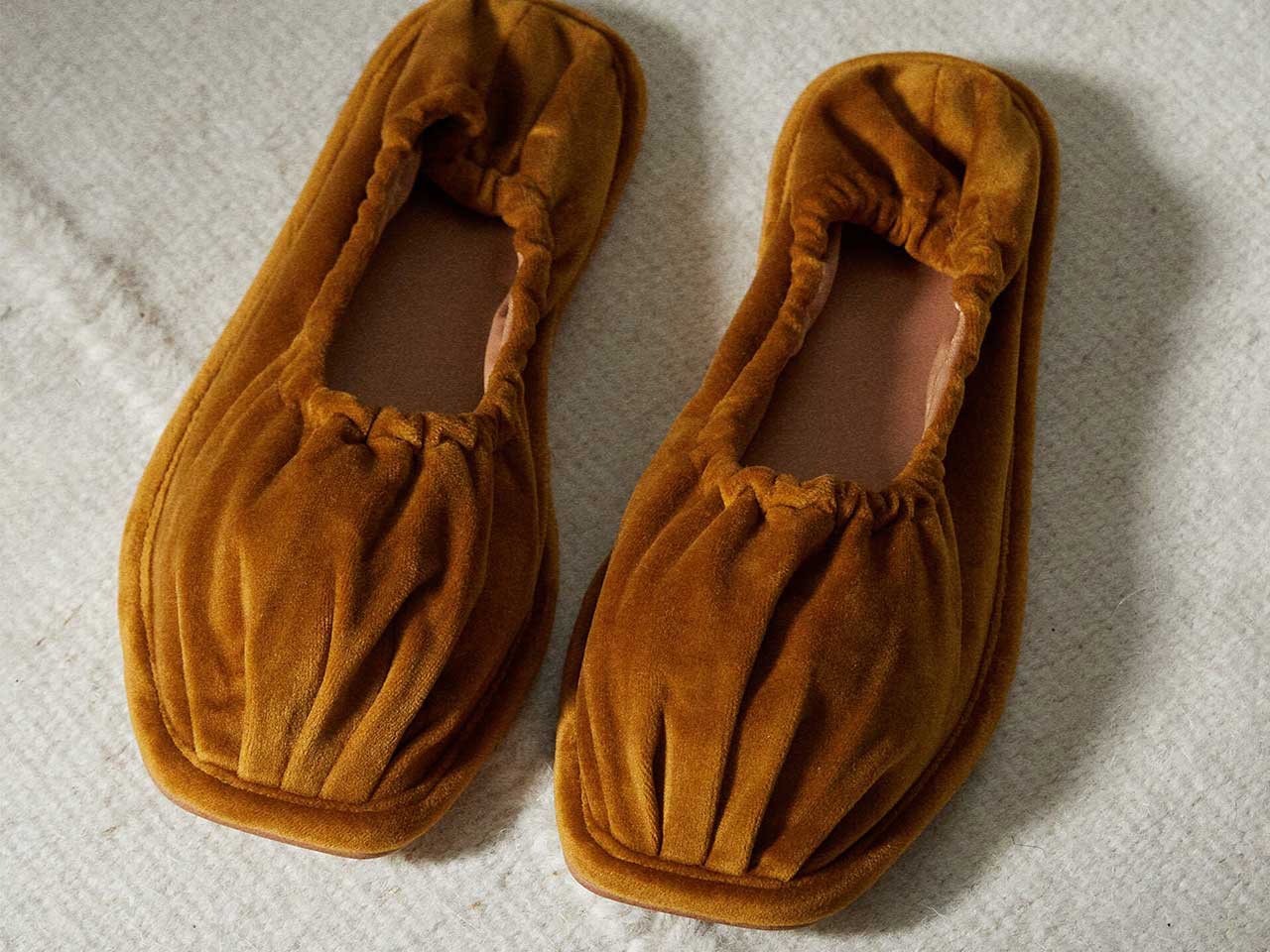 A pair of brown velvet ballerina slippers seen from above.