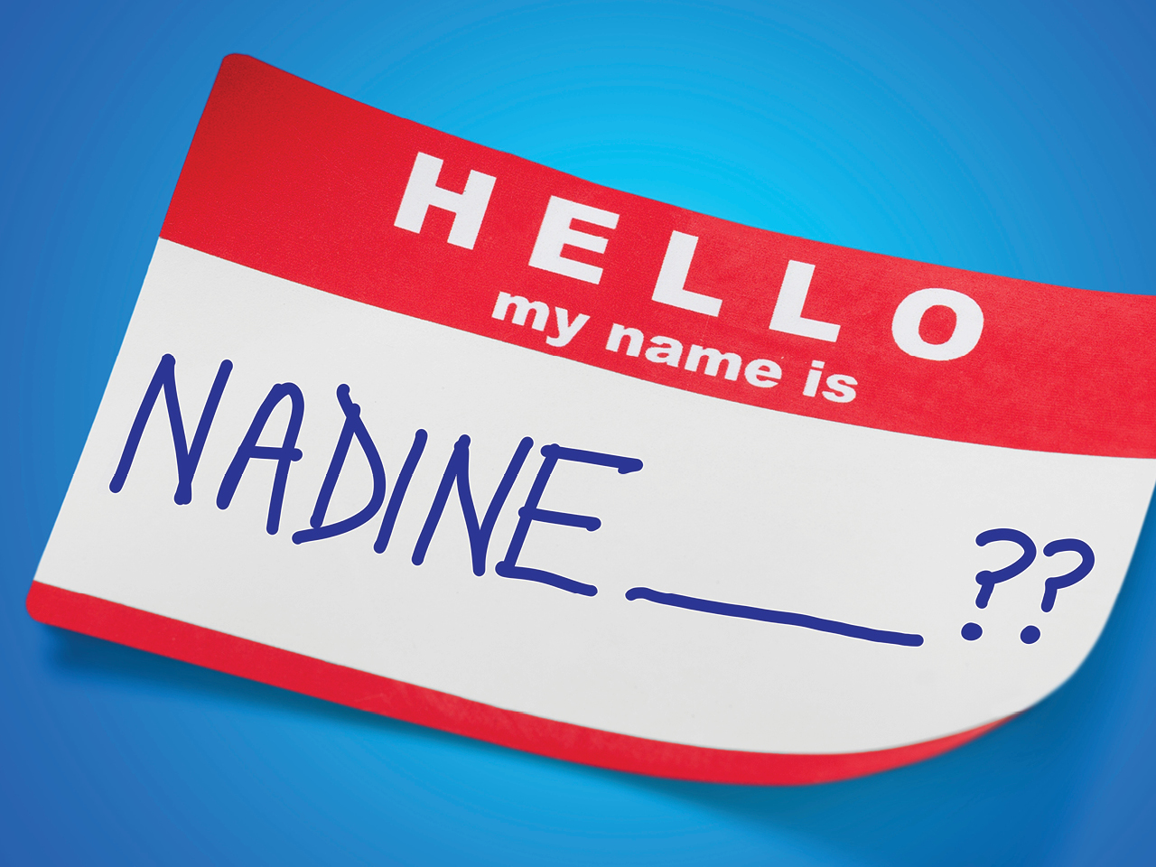A classic "Hello, my name is" name tag in red and white with Nadine and question marks written on it in marker on a blue background