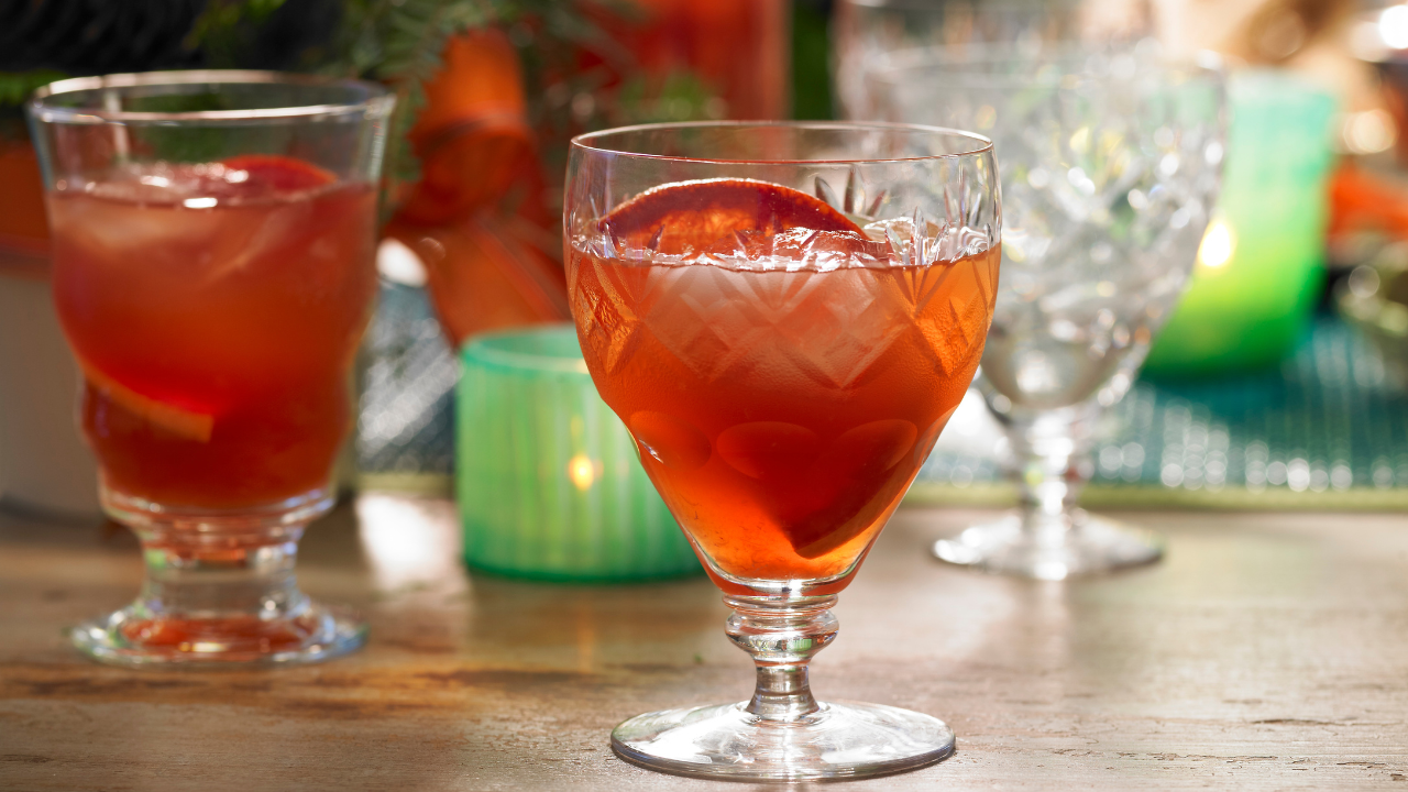 Two glasses of red punch sits on a festive-looking tablescape